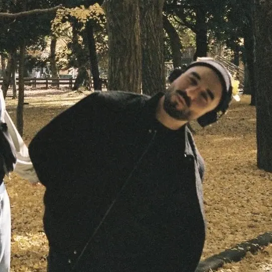 A black-clad man with a beanie in an autumn park